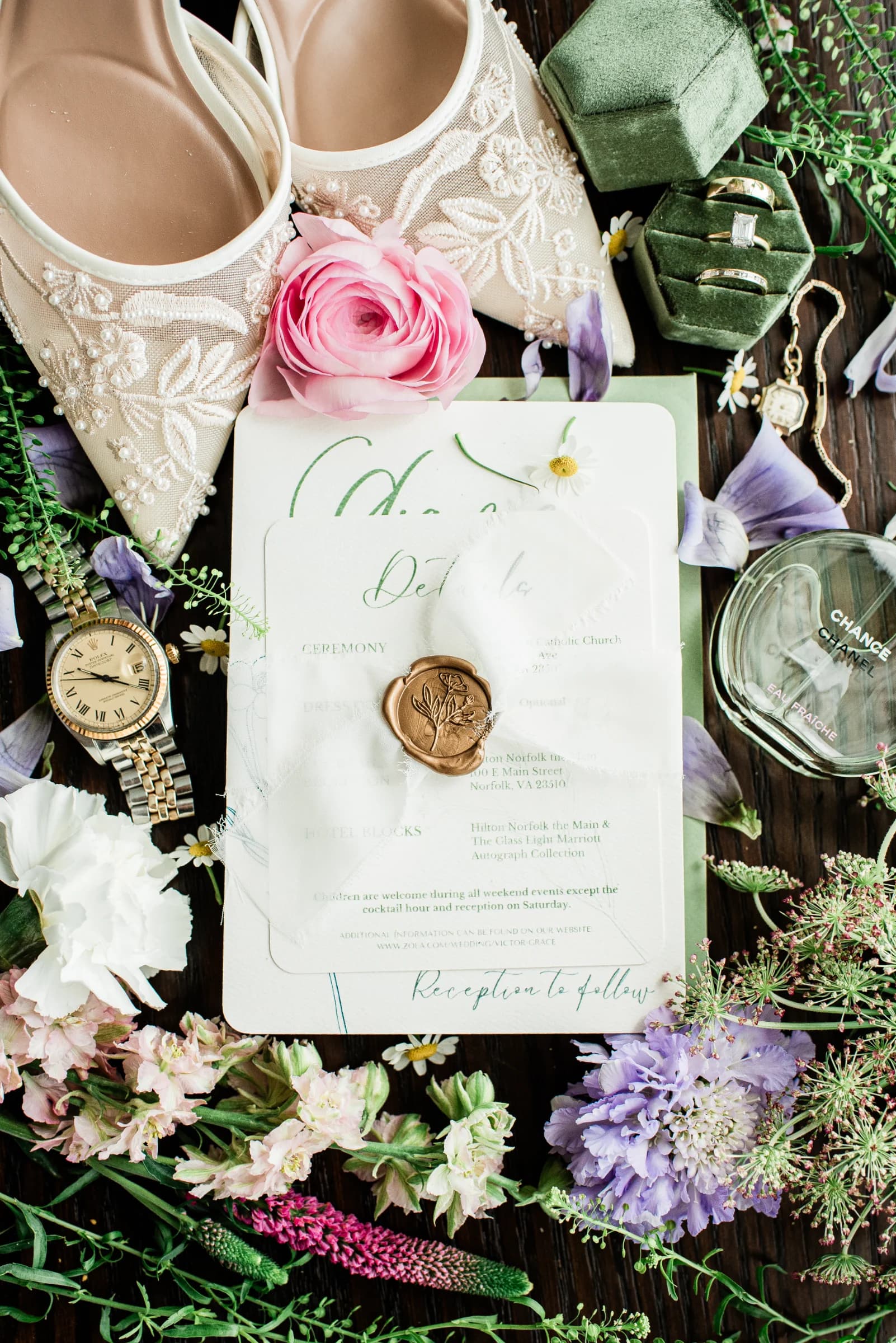 Elegant wedding details featuring floral arrangements, a pair of embellished shoes, and a beautifully designed invitation.